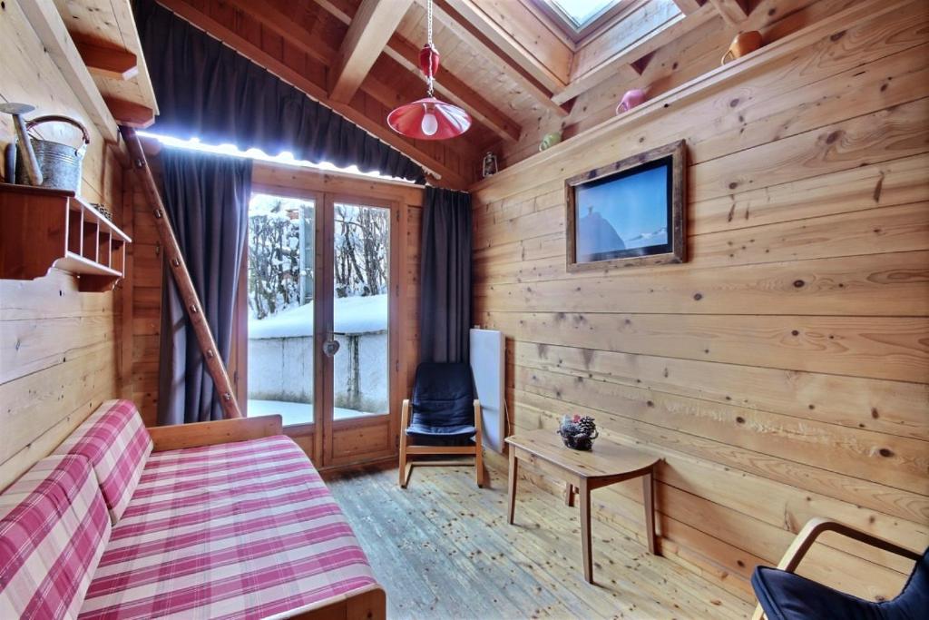 a log cabin bedroom with a bed and a tv at Appartement à 600m des remontées mécaniques, centre Morzine, chalet les Joux in Morzine