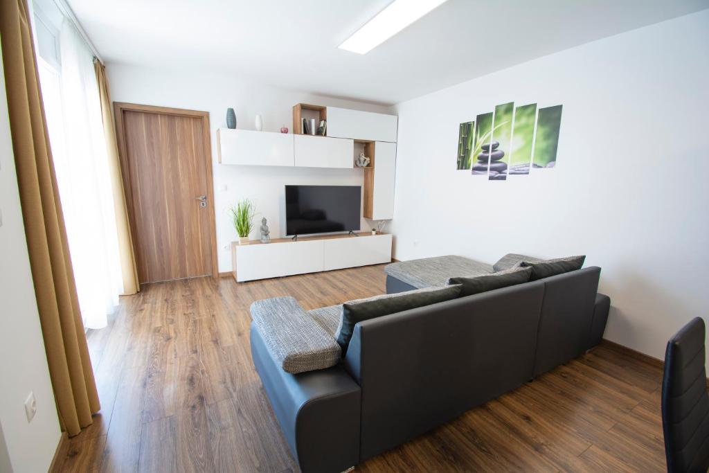 a living room with a couch and a tv at ÁbraApartman in Siófok