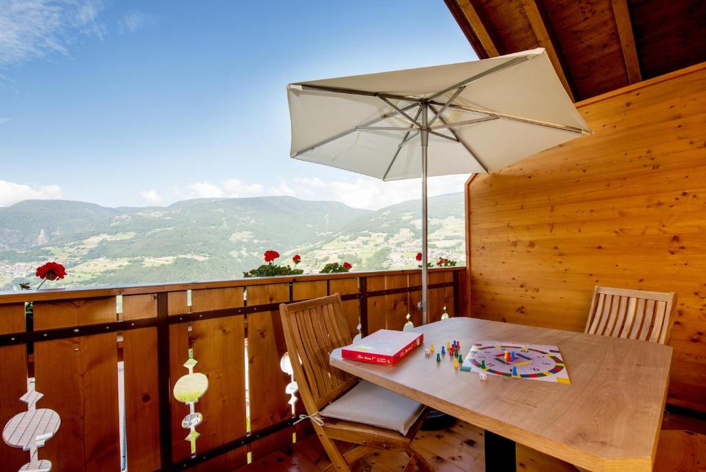 una mesa y sillas con una sombrilla en el balcón en Haus Sonnegg Familiensuite, en Laion