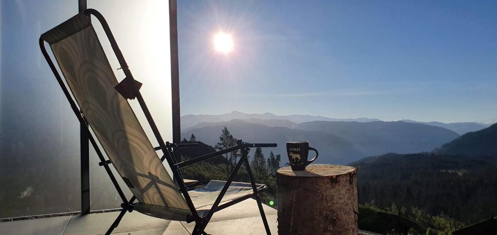 uma cadeira sentada num toco com vista para as montanhas em Tiny mountain cabin with a panoramic view em Giljane