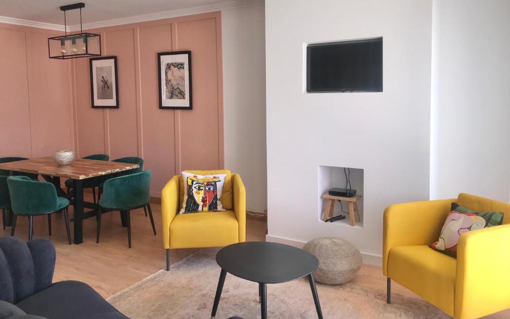 a living room with yellow chairs and a table at Casa do Sol in Sesimbra