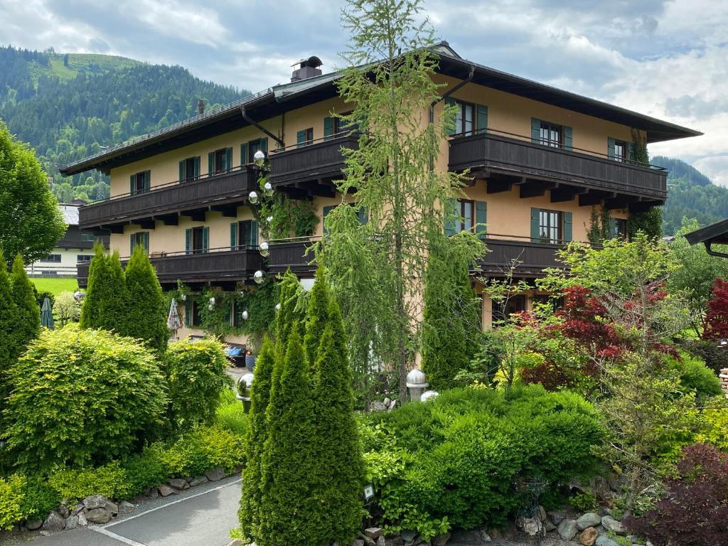 un grand bâtiment avec beaucoup d'arbres et de buissons dans l'établissement Hotel Edelweiss Kitzbühel, à Kitzbühel