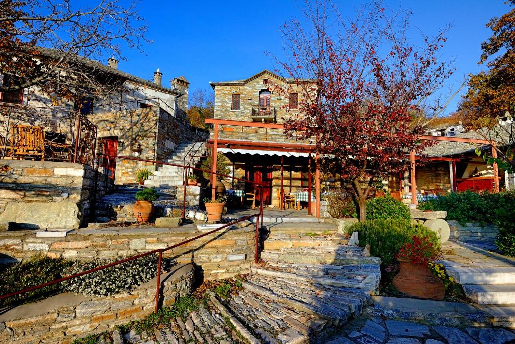 an old stone house with a staircase in front of it at Anovolios Boutique Hotel in Agios Georgios Nilias