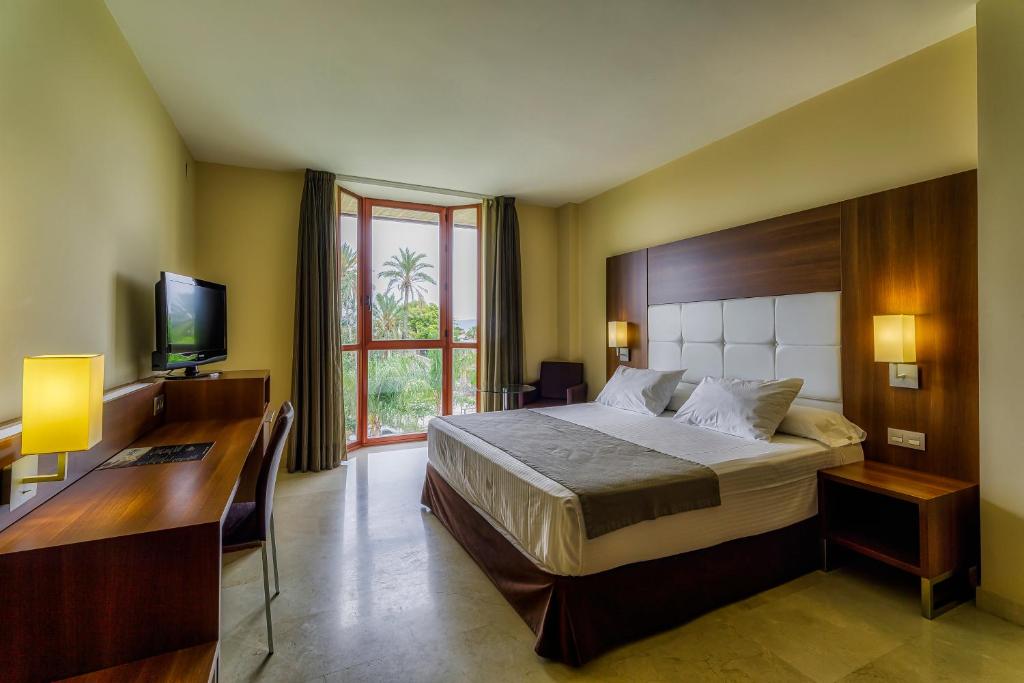 a bedroom with a bed and a desk and a television at Spa Jardines de Lorca in Lorca