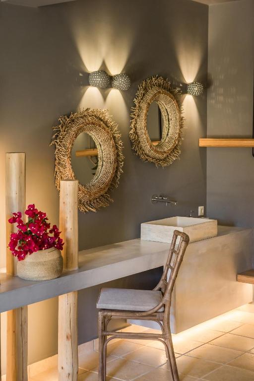 a bathroom with a table and a chair and mirrors at Avithos Resort Hotel in Svoronata