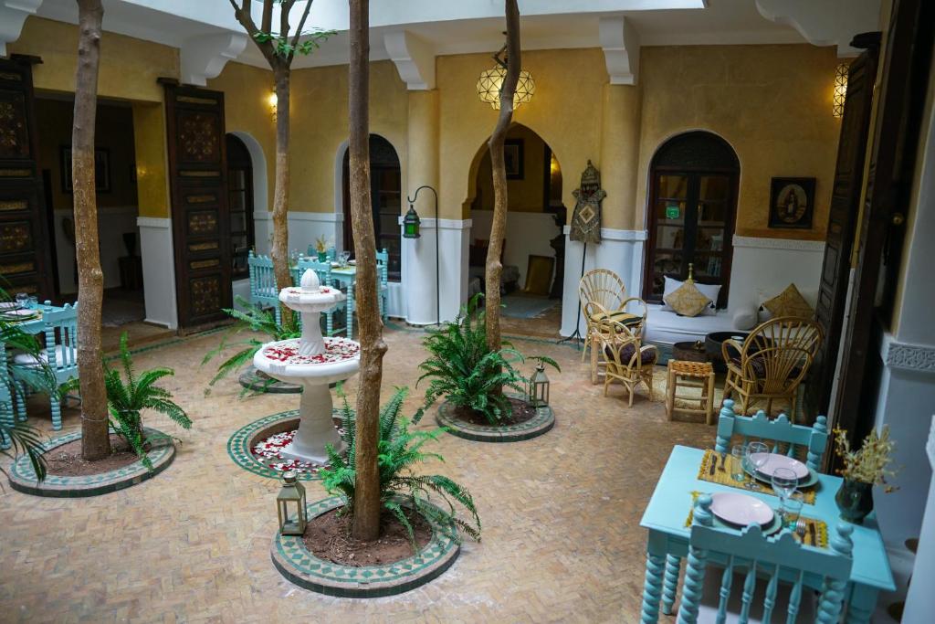 uma sala com mesas e cadeiras e palmeiras em Riad Dama & Spa em Marrakech