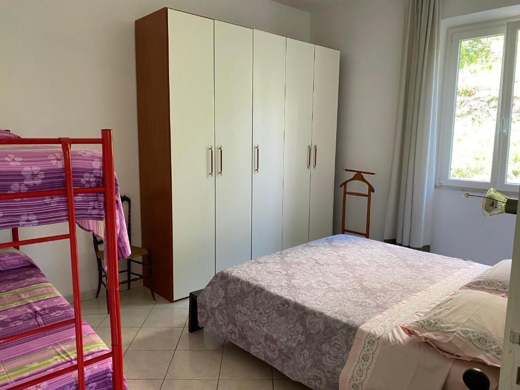 een slaapkamer met een bed, witte kasten en een raam bij Là Mì Cà in La Spezia