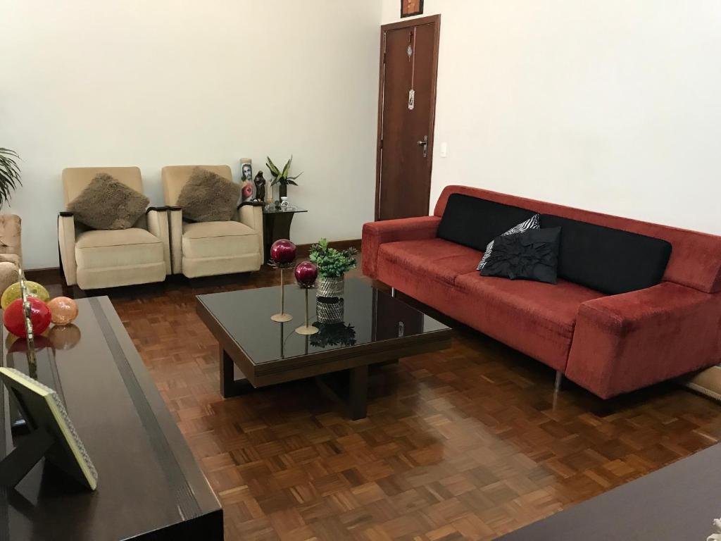 uma sala de estar com um sofá vermelho e uma mesa em Apartamento Mar da Praia da Costa em Vila Velha
