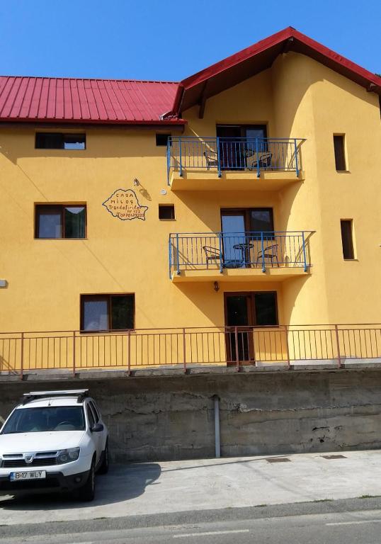a white car parked in front of a yellow building at Casa MILOS SI FIUL in Băile Herculane