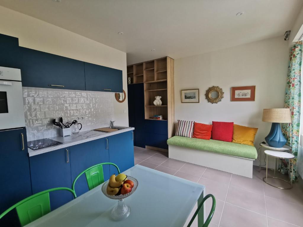 een keuken met blauwe kasten en een tafel met een fruitschaal bij Appartement Escapade Vitaminée - Maison d'Aligre in Marans