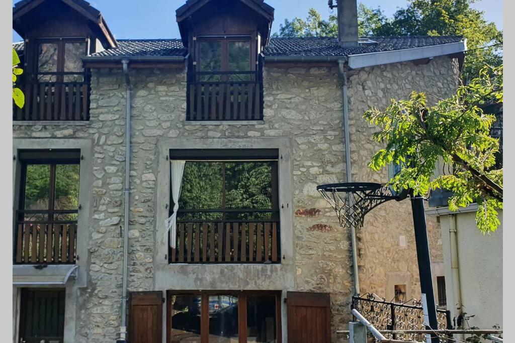 Perles-et-Castelet的住宿－Maison au cœur des Pyrénées，一座石头房子,设有两扇窗户和篮球架