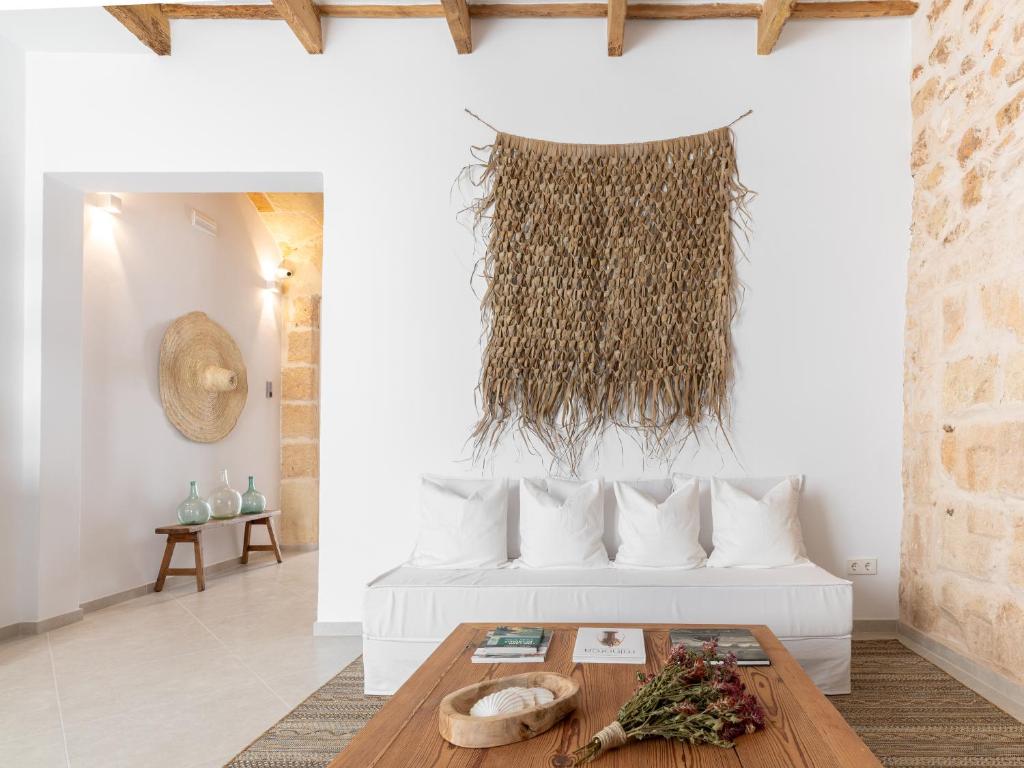 uma sala de estar com uma cama e uma mesa em S'Enclova Petit Hotel em Ciutadella