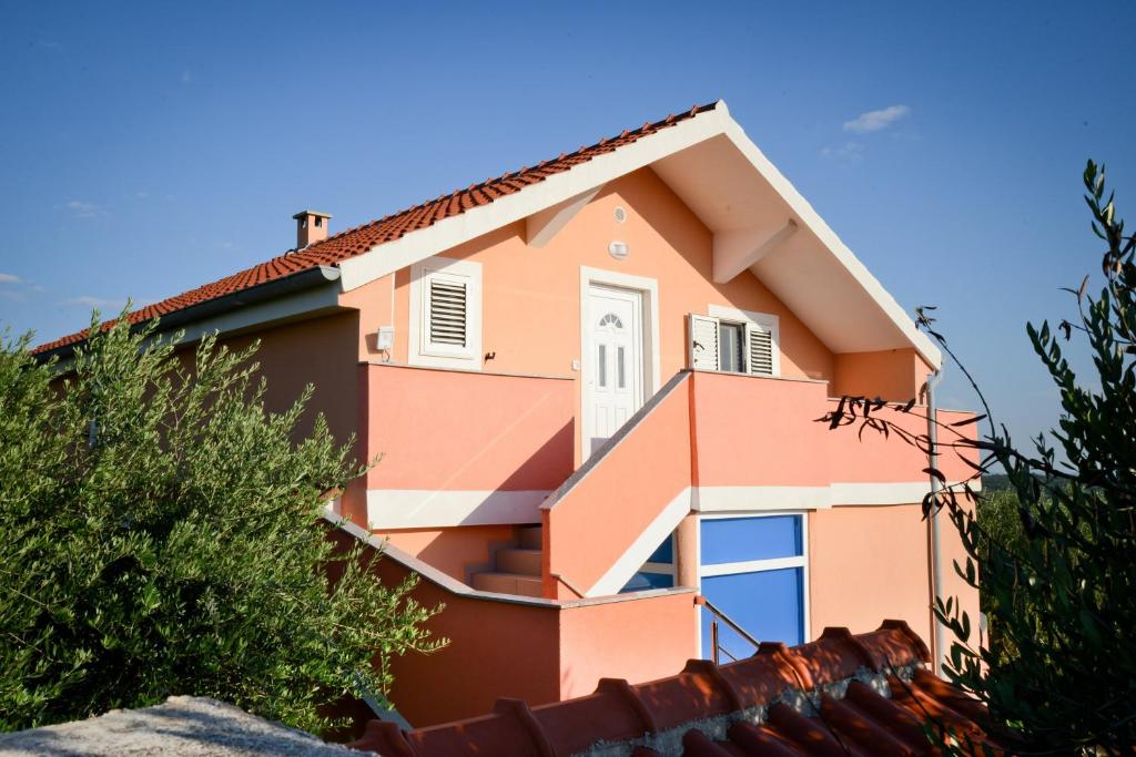 un edificio rosa con un cielo azul en el fondo en Apartman Olive 01, en Zadar