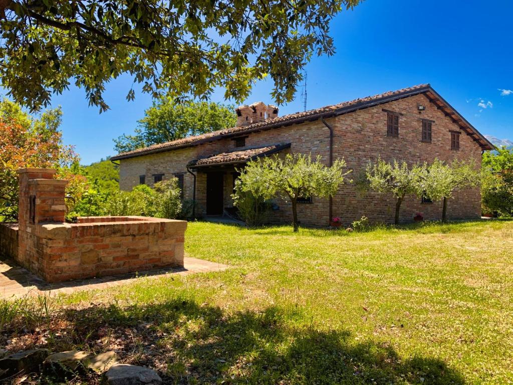 an old brick building in a field of grass at Villa Le Brugnolete - Appartamento Est in Sarnano