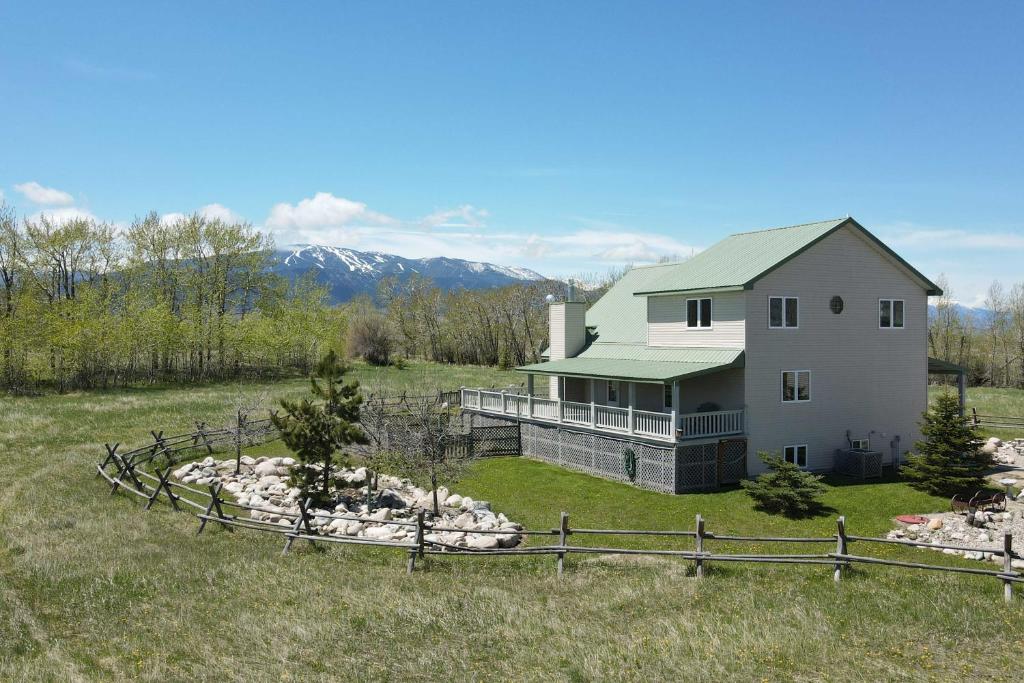 a white house with a green roof in a field at The Front Porch 20-Acre Country Home with Mtn View in Red Lodge