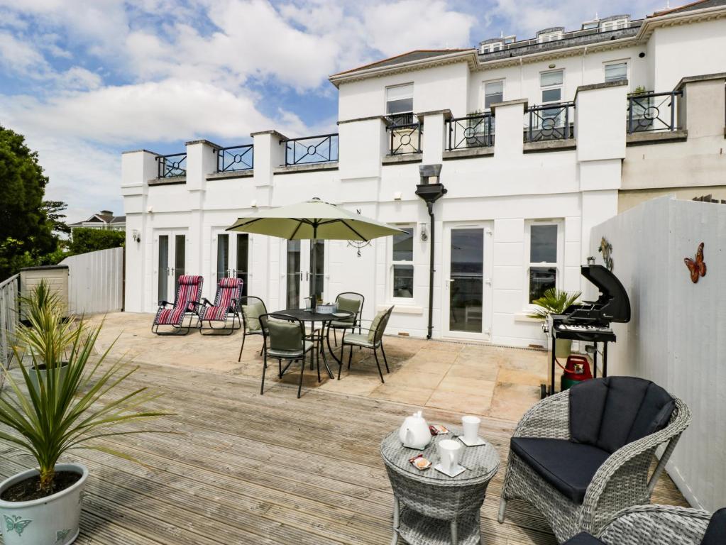 a patio with chairs and a table on a building at Waves, The Bay in Torquay