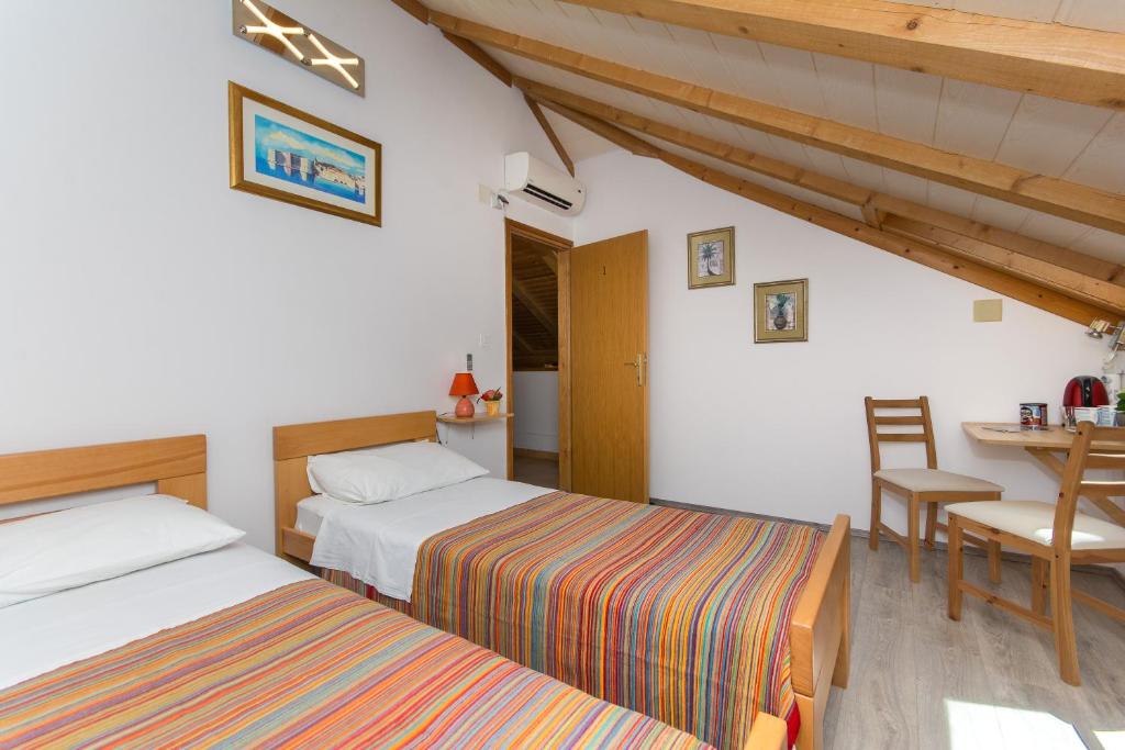 a bedroom with two beds and a table and a table and chairs at Tomato Old Town entrance in Dubrovnik