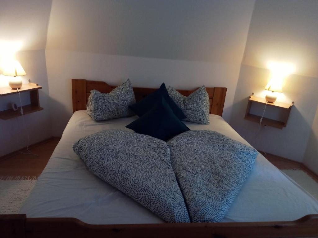um quarto com uma cama com almofadas e 2 candeeiros em Elo Apartman em Csokonyavisonta