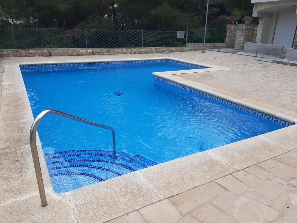 a large blue swimming pool with a hand rail in a yard at Gaviotas piscina comunitaria in Calafat