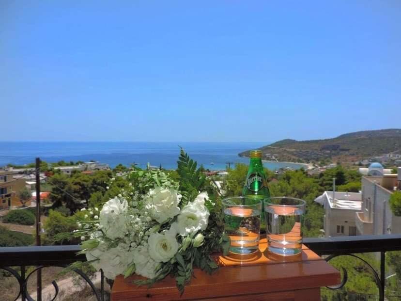 een tafel met bloemen en een fles en glazen bij Vana Studios in Agia Marina Aegina
