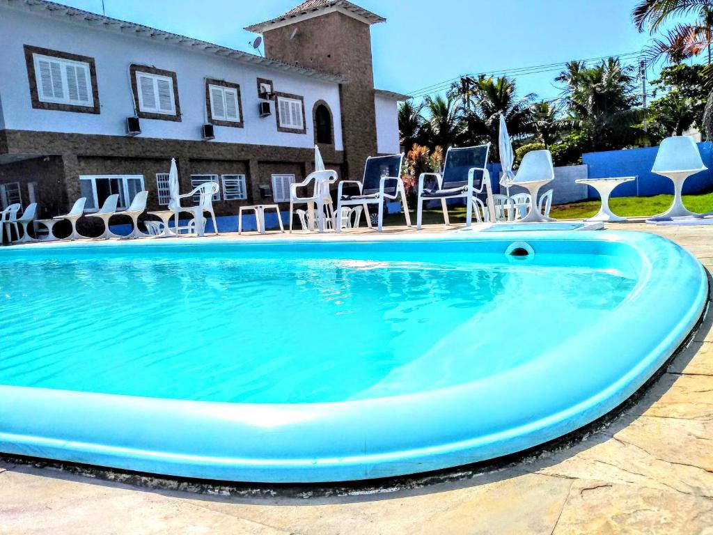 - une piscine avec des chaises et une maison dans l'établissement Pousada Hotel Canto dos Mares, à Guarujá