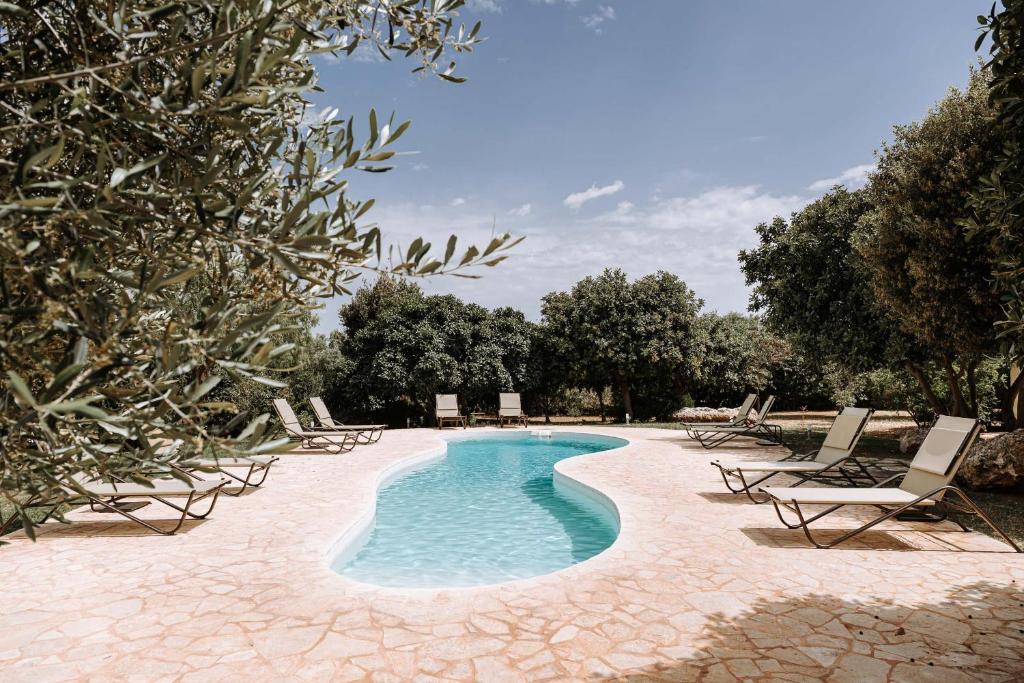 einen Pool mit Chaiselongue und Bäumen in der Unterkunft Masseria Garrappa in Fasano