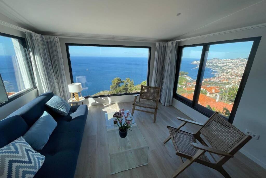 een woonkamer met een blauwe bank en een aantal ramen bij Blue Infinity, Aquamarine apartment in Funchal