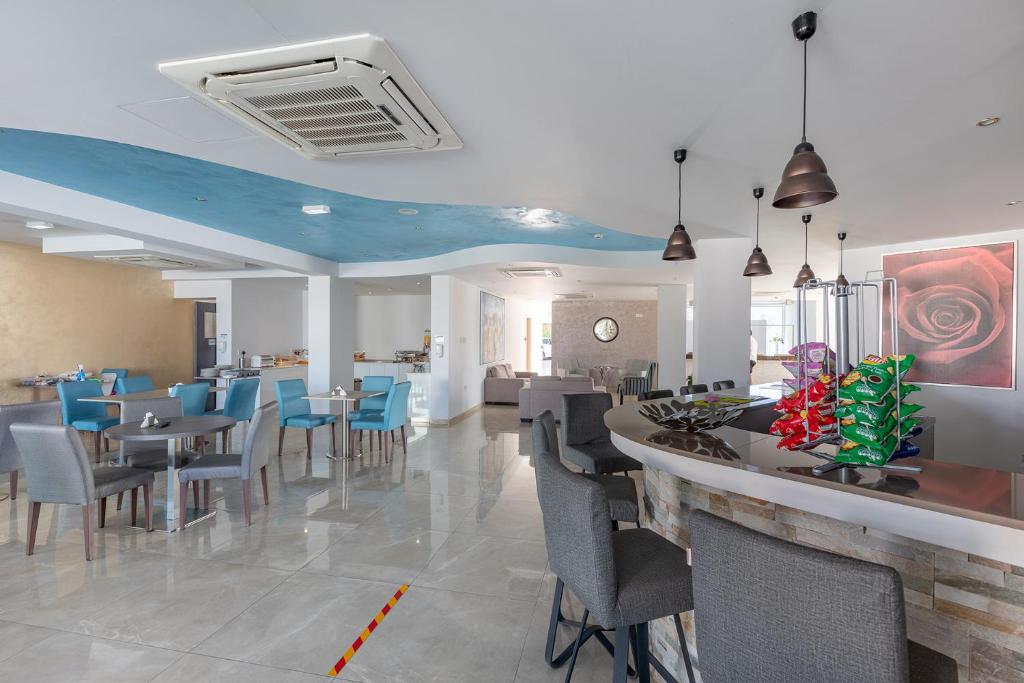 a restaurant with chairs and tables and a bar at Bellini Hotel in Ayia Napa