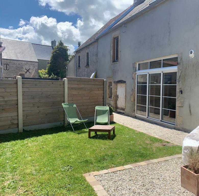 a yard with two chairs and a fence at Villa kahlo Omaha Beach in Colleville-sur-Mer