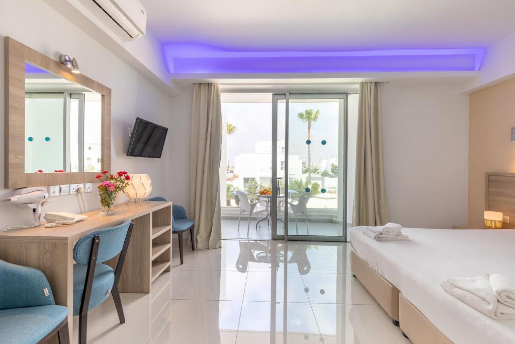a hotel room with a bed and a desk and a room at Bellini Hotel in Ayia Napa