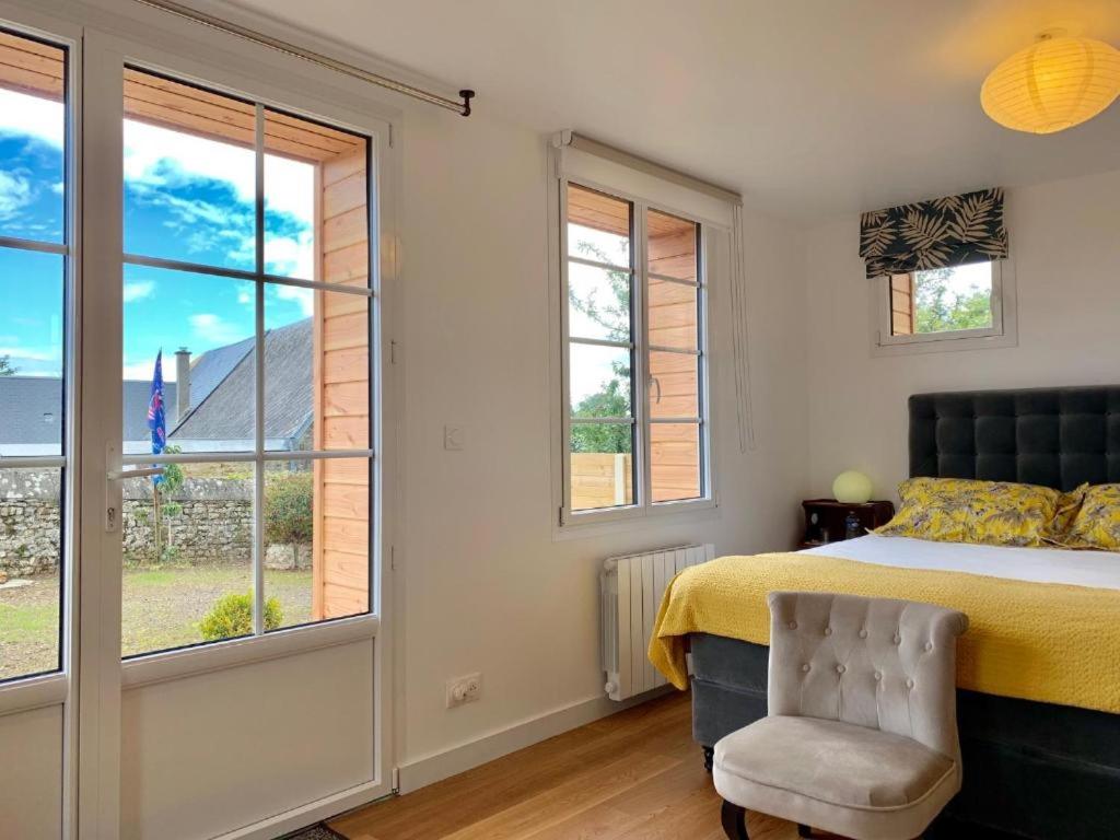 a bedroom with a bed and a chair and windows at Villa kahlo Omaha Beach in Colleville-sur-Mer