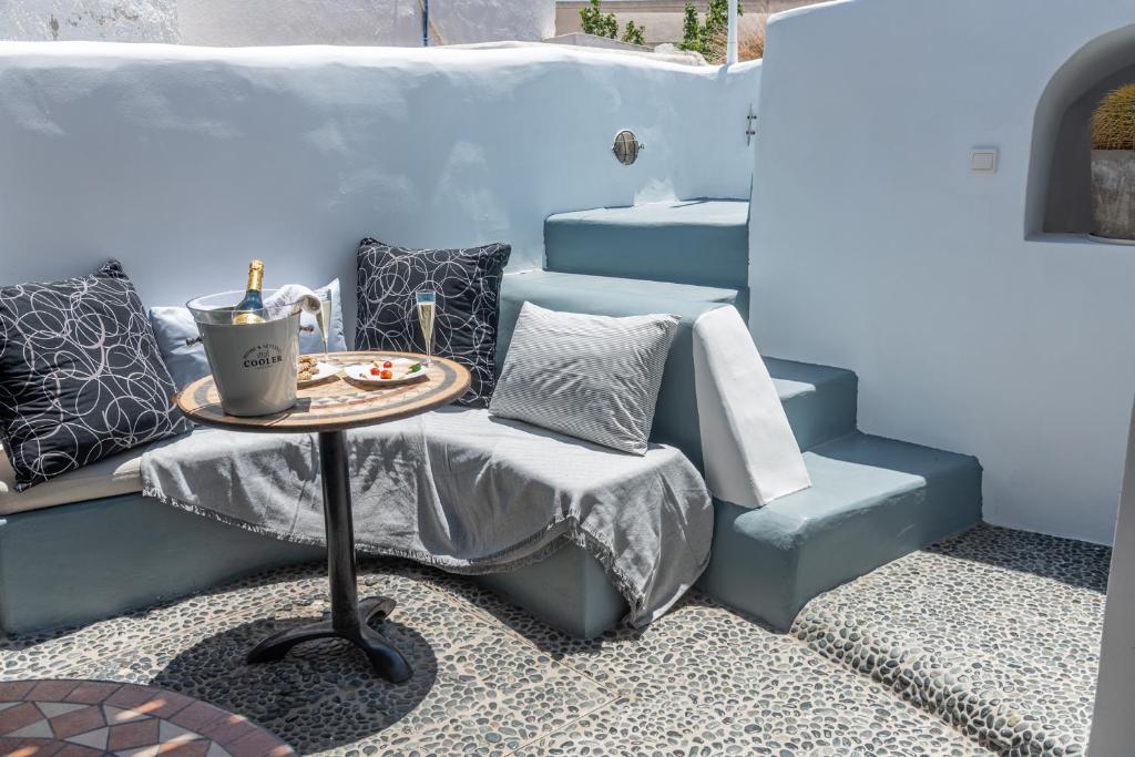 a patio with a table and a couch and some pillows at Villa Orpheus Santorini in Megalokhori