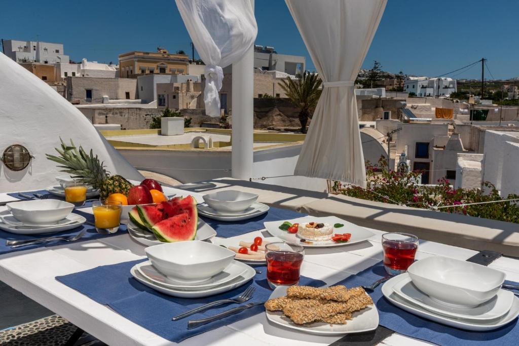 a table with plates of food on top of a balcony at Villa Orpheus Santorini in Megalokhori