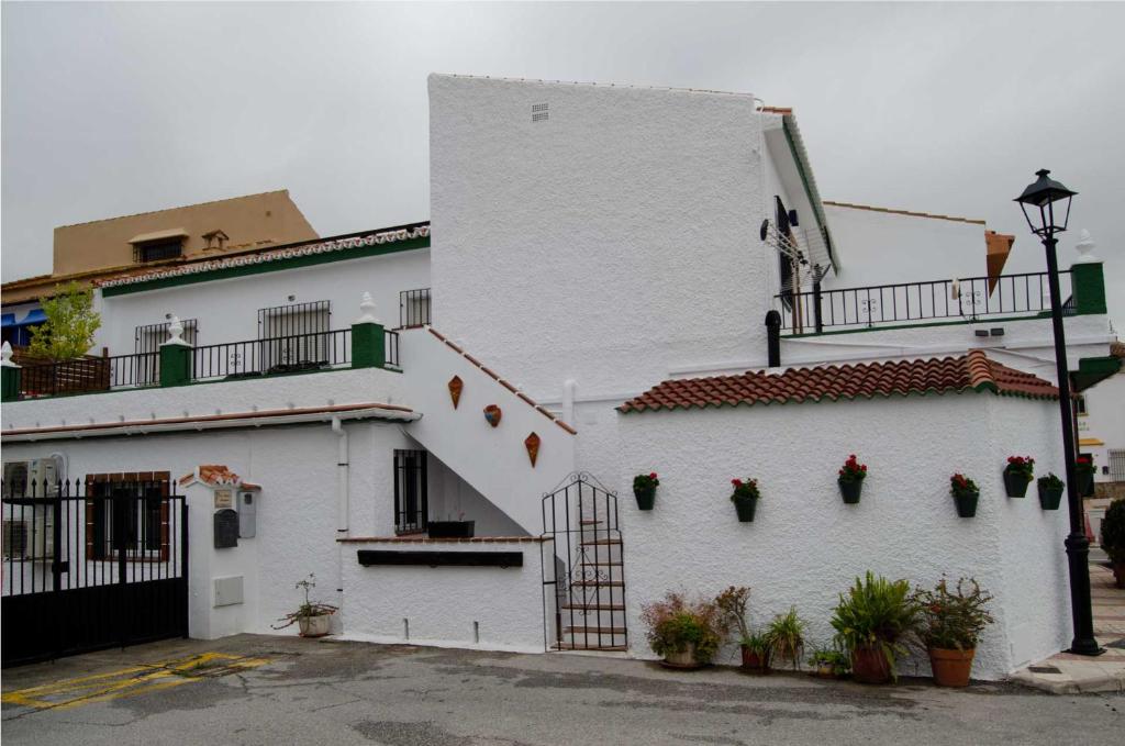 un bâtiment blanc avec des plantes en pot sur son côté dans l'établissement Zapata Home, à Alhaurín de la Torre
