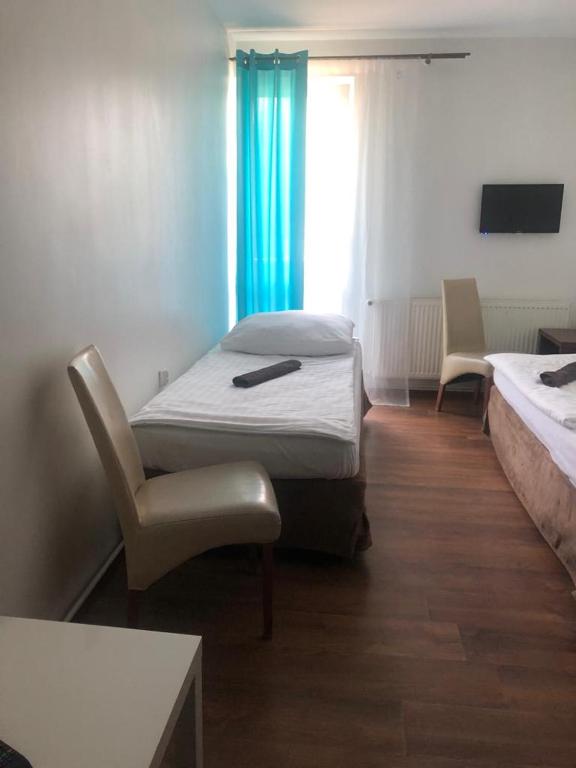 Cette chambre dispose de deux lits, d'une chaise et d'une fenêtre. dans l'établissement Hotel Niedźwiedź, à Wonieść