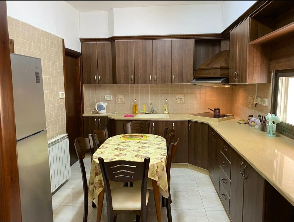 a kitchen with a table with chairs and a refrigerator at Joseph apartment in Bethlehem