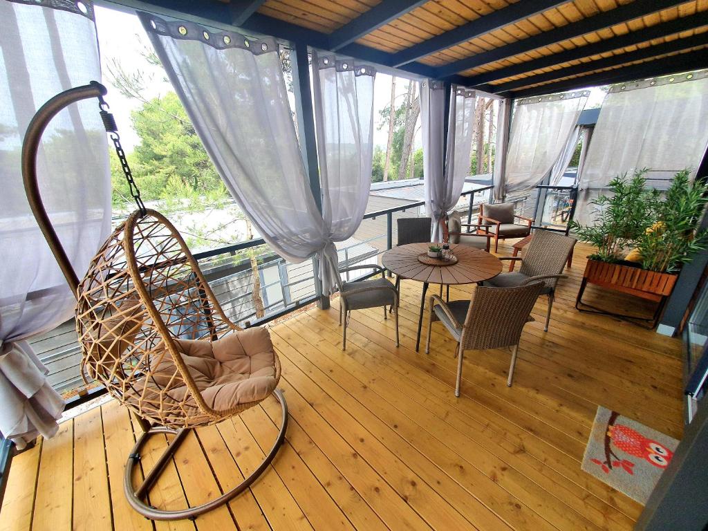 Mobile Home Leggiero 156 - Porton Nature Hideouts في روفينج: غرفة مع كرسي هزاز وطاولة على شرفة