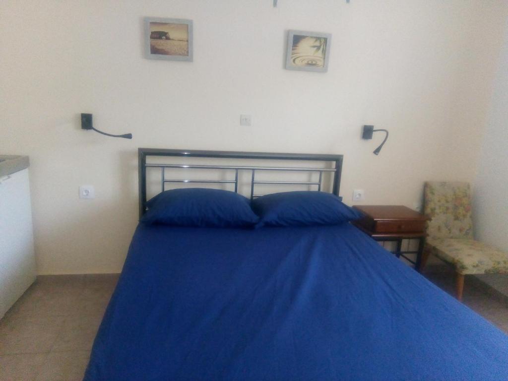 um quarto com uma cama azul e uma cadeira em Balcony to Aegeon 3 em Apollon