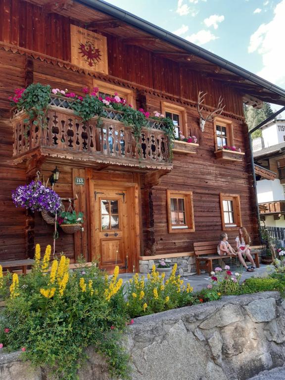 una cabaña de madera con flores delante en Haus Elfriede, en Schwendau