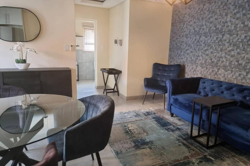 ein Wohnzimmer mit einem blauen Sofa und Stühlen in der Unterkunft Koena Court (Unit 2) - With Uncapped Fiber Wi-Fi in Midrand
