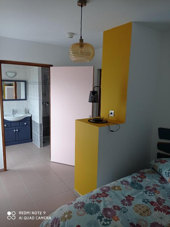 - une chambre avec un lit et un mur jaune dans l&#39;établissement ferme de fenivou, à Boulieu-lès-Annonay