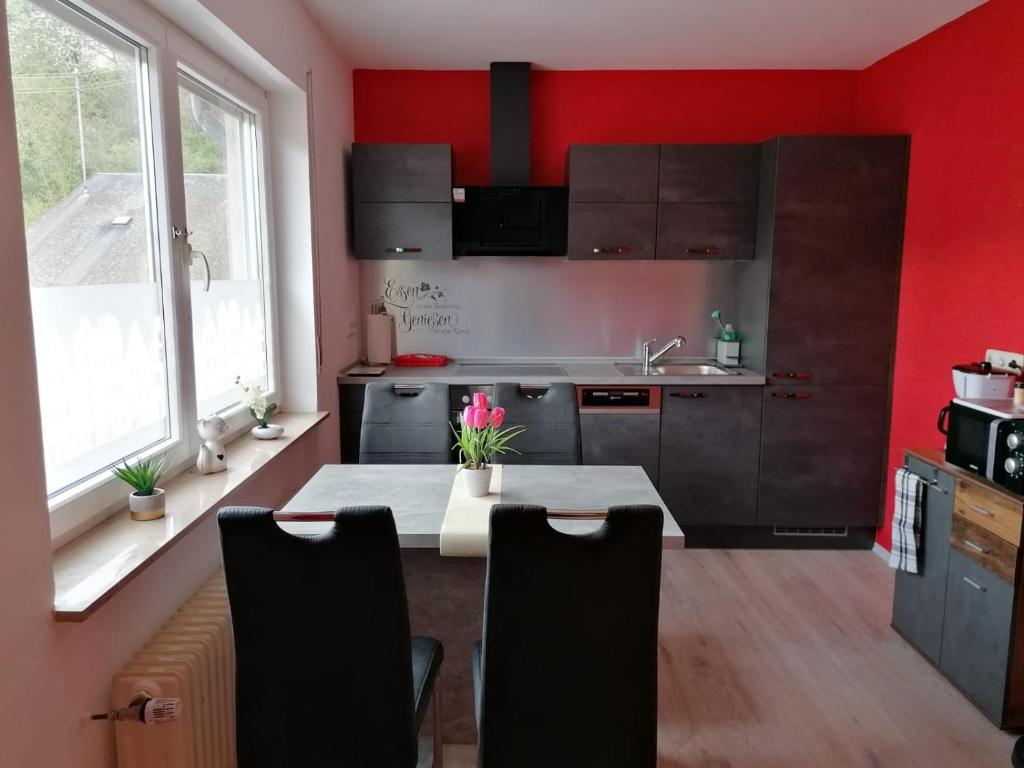 a kitchen with red walls and a table with chairs at Enscher Stübchen Wohnung Katharina in Ensch