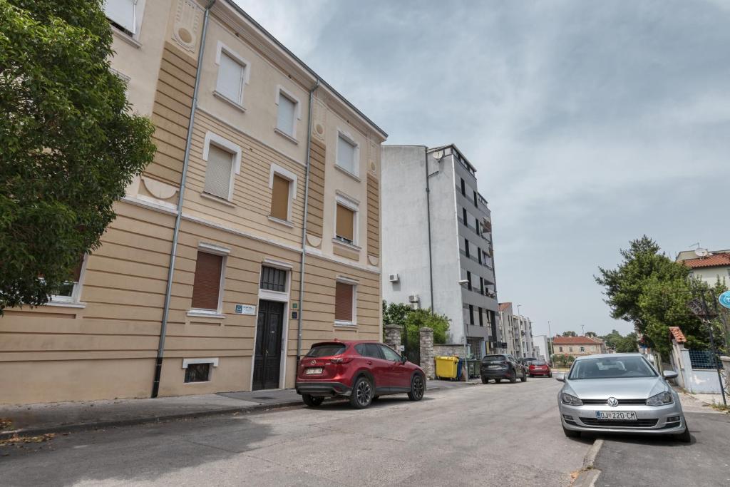two cars parked on a street next to a building at Apartment light in Pula in Pula