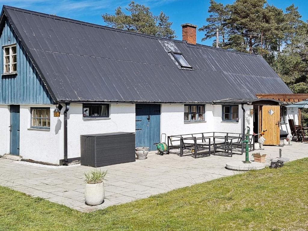 a white house with a black roof and a patio at 6 person holiday home in L derup in Löderup
