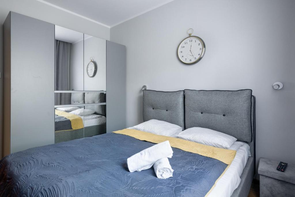 Un dormitorio con una cama con un reloj en la pared. en JM 2 STATION APARTMENT - Bosacka street near old town, en Cracovia