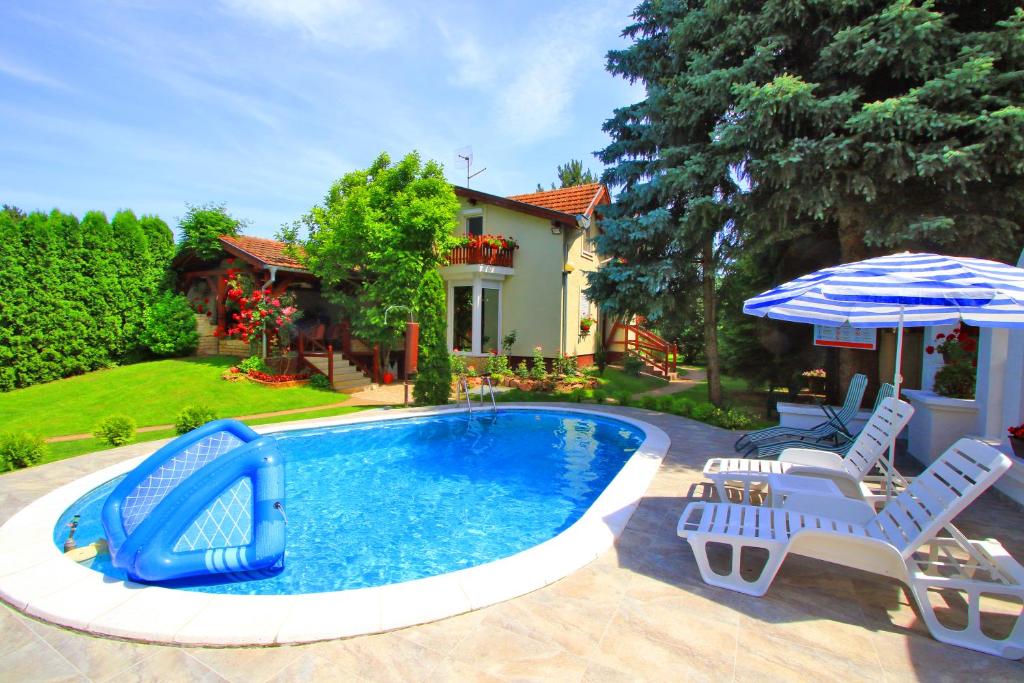 uma piscina com escorrega, duas cadeiras e um guarda-sol em Šumski raj em Subotica