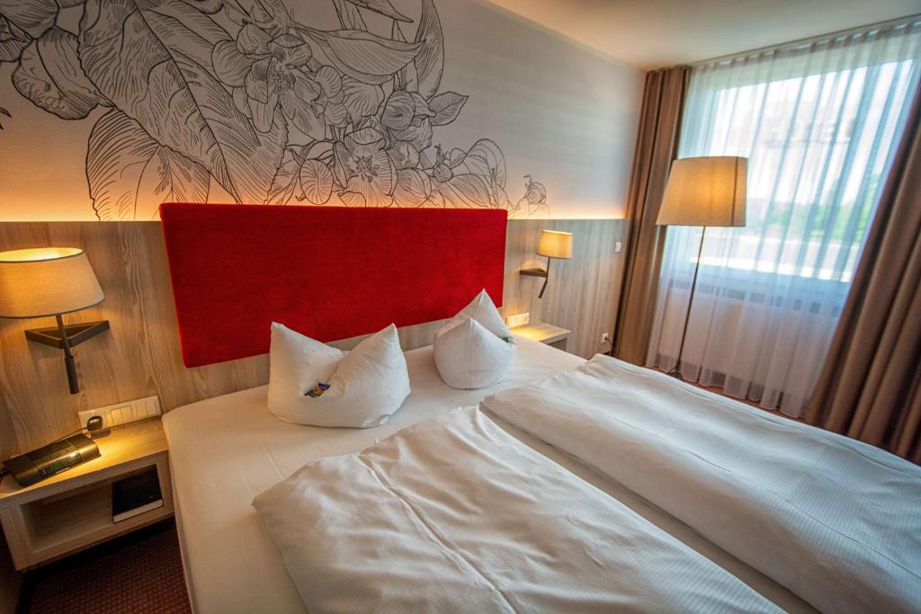 a bedroom with a large white bed with two pillows at Best Western Erfurt-Apfelstädt in Erfurt