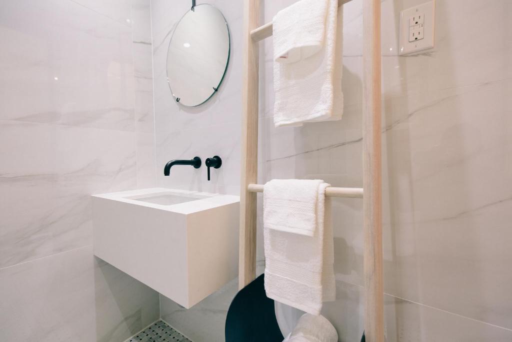 a white bathroom with a sink and a mirror at Ode in Toronto