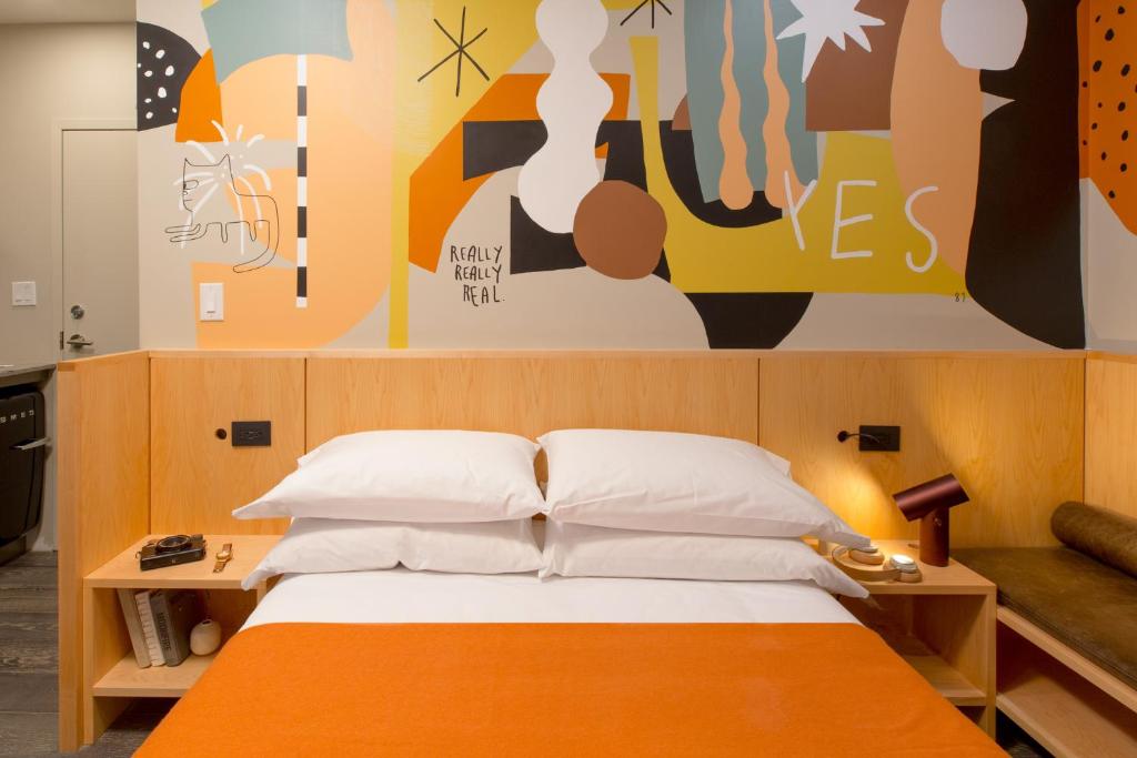 a bedroom with an orange and white bed and a painting at Ode in Toronto