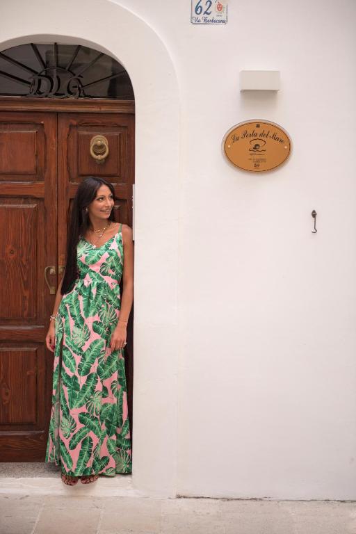 a woman in a dress standing in front of a door at La Perla del Mare in Monopoli